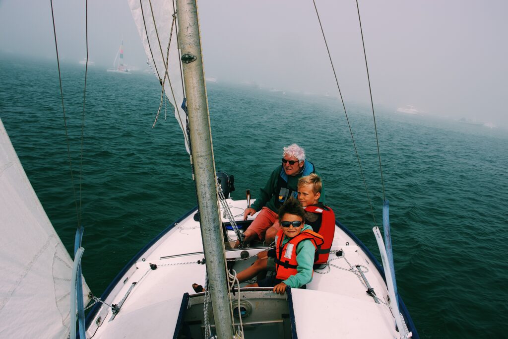 grandfather and grandchildren sailing together on a sailboat