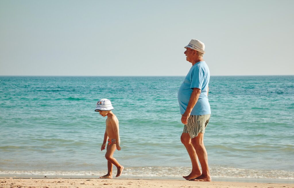 grandfather walking along a beach with his young grandson