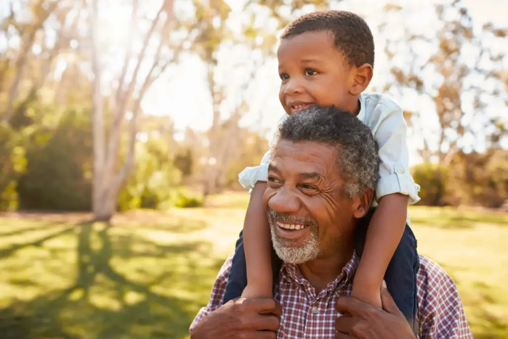 smiling grandfather carrying his grandson on his shoulders