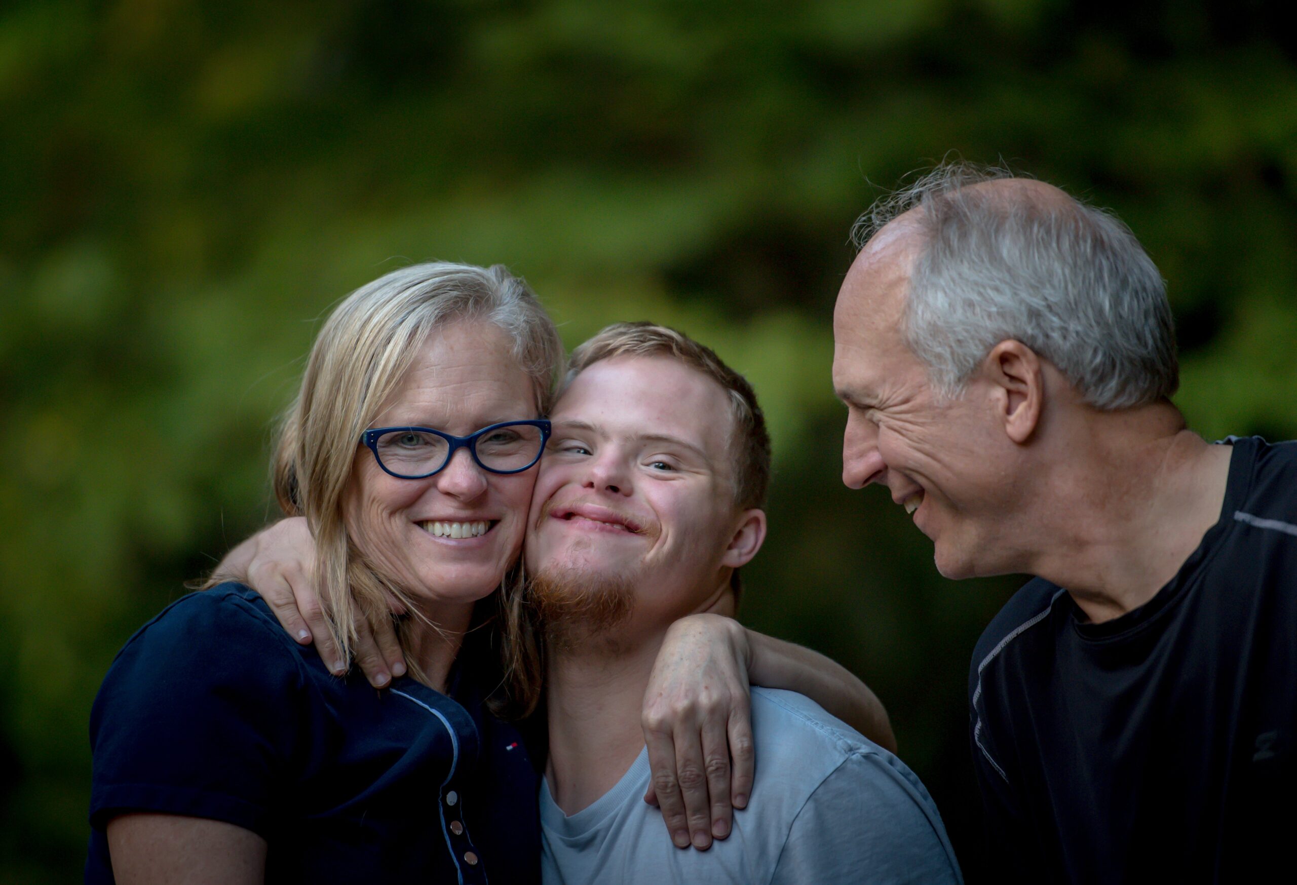 parents smiling and embracing their son with down syndrome