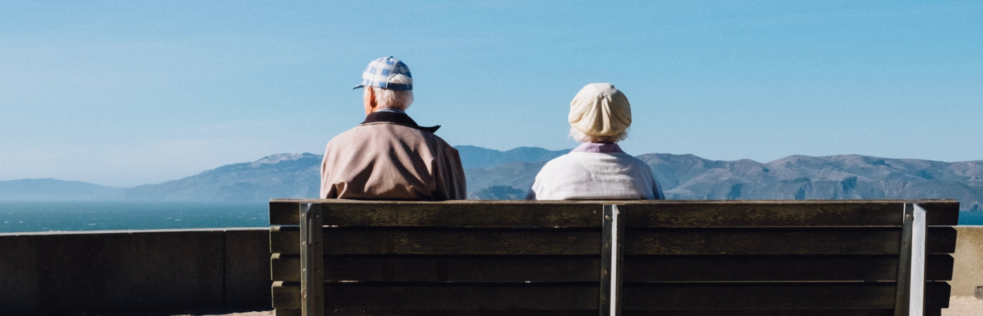 retired couple sitting on a bench together and viewing the landscape
