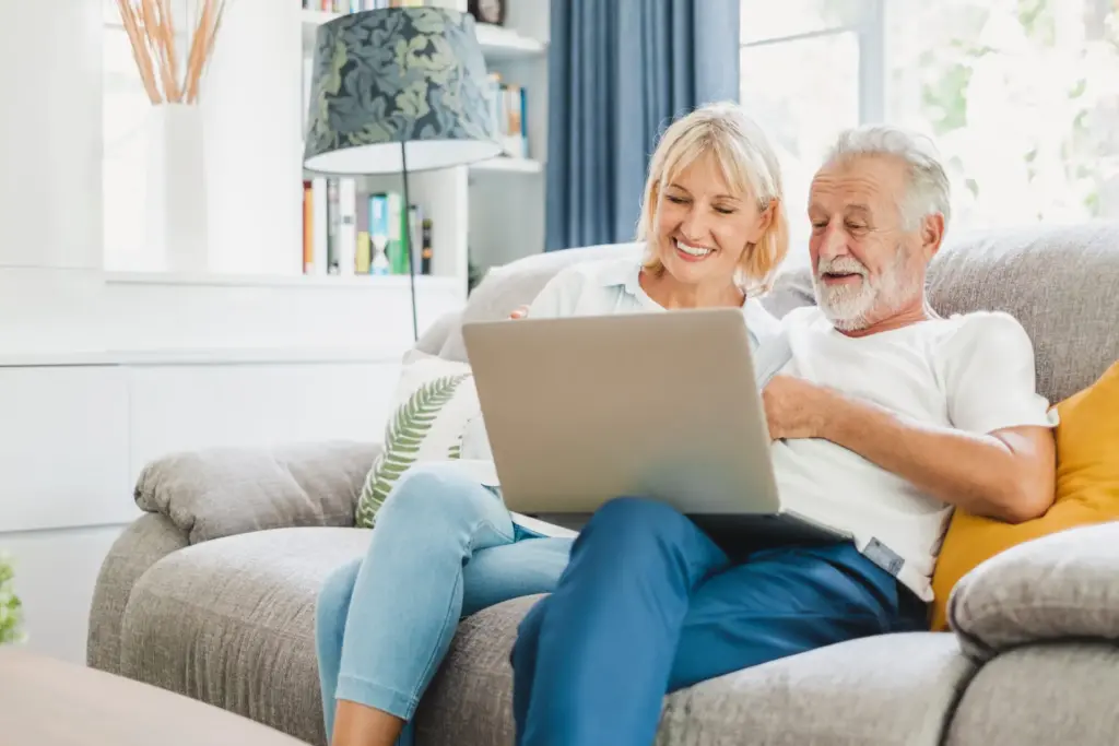 senior couple sitting together on their couch with a laptop