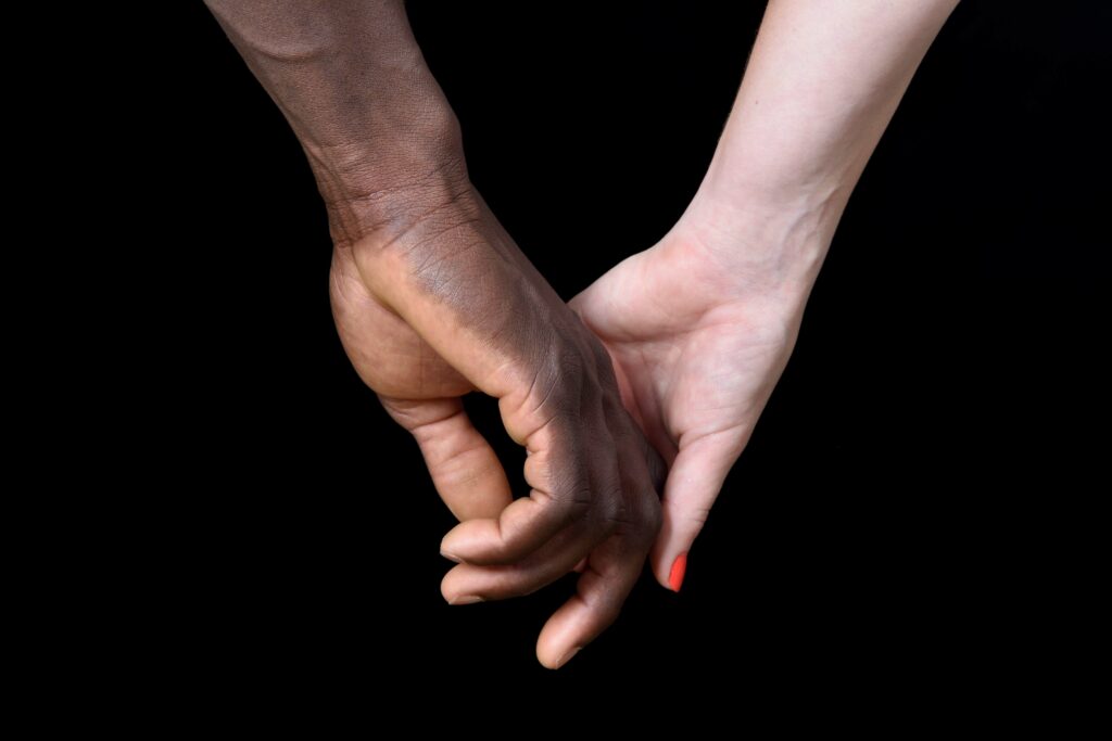 man and woman holding hands against a black background