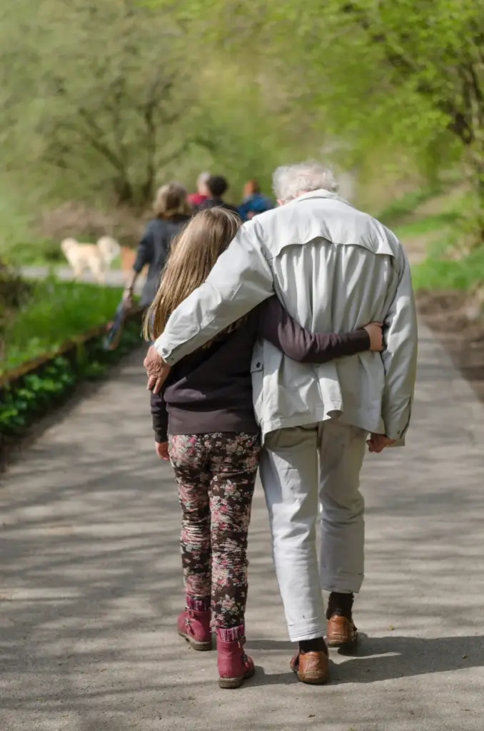grandfather and granddaughter walking together in a park