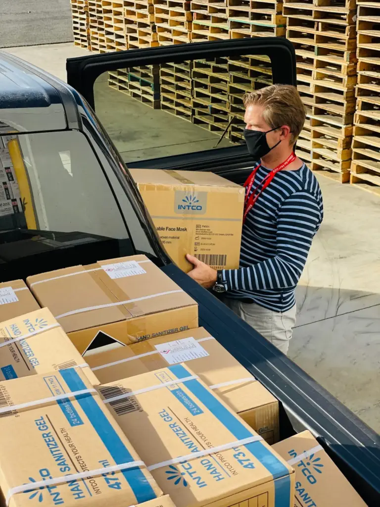 man wearing a mask and loading boxes into a truck